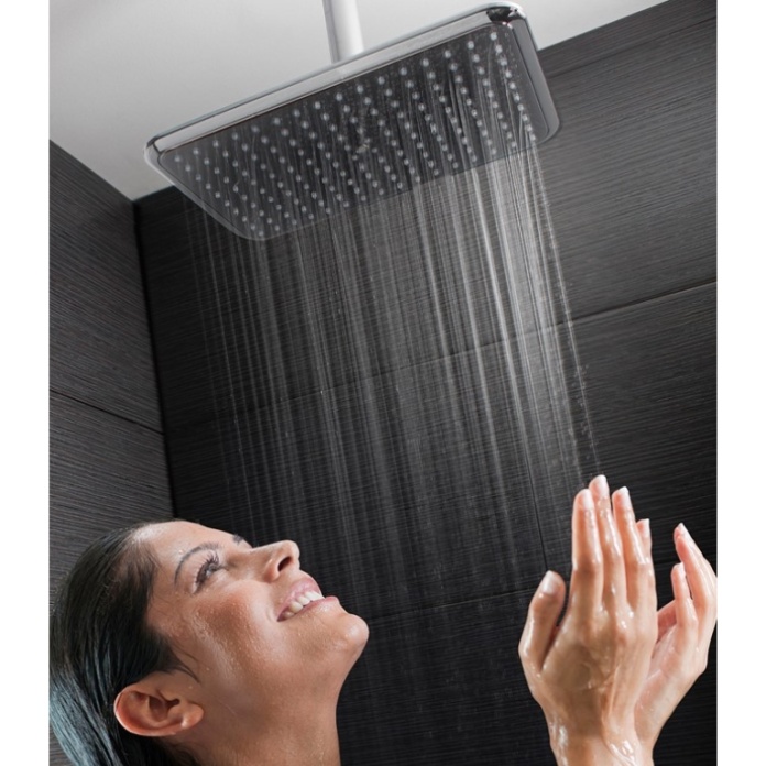 Product Lifestyle image of a happy smiley woman, not holding hands, but standing underneath the Crosswater Essence Easy Clean Shower Head with Shower Arm
